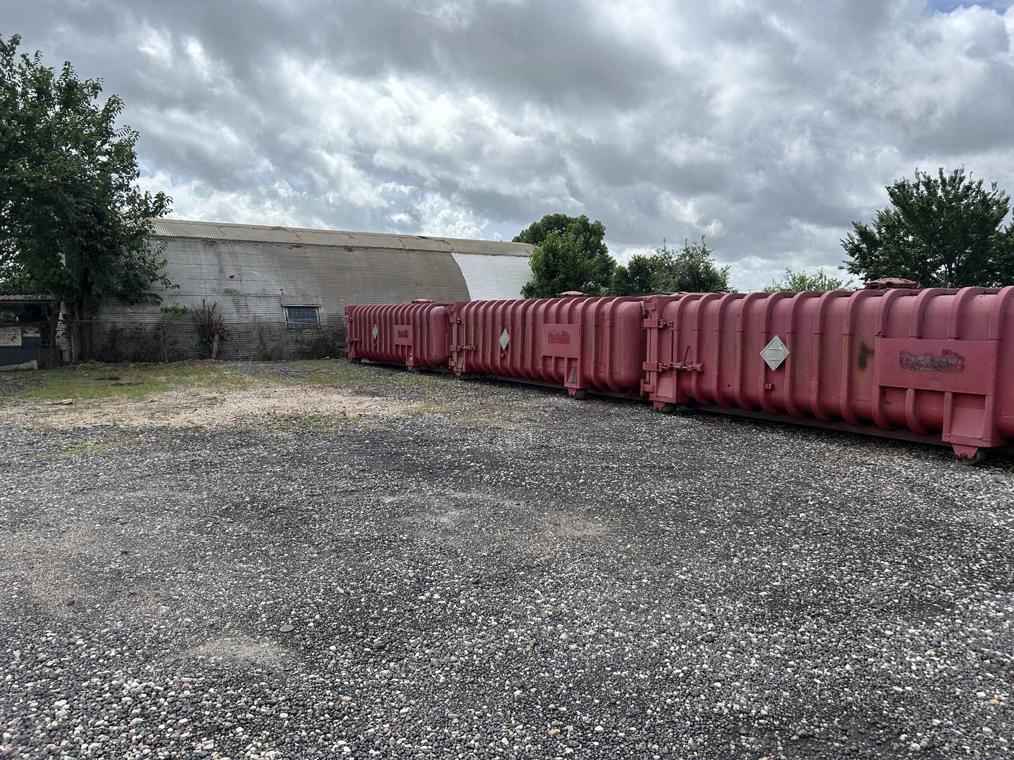 Row of used Roll-Off Vacuum Tanks along a building