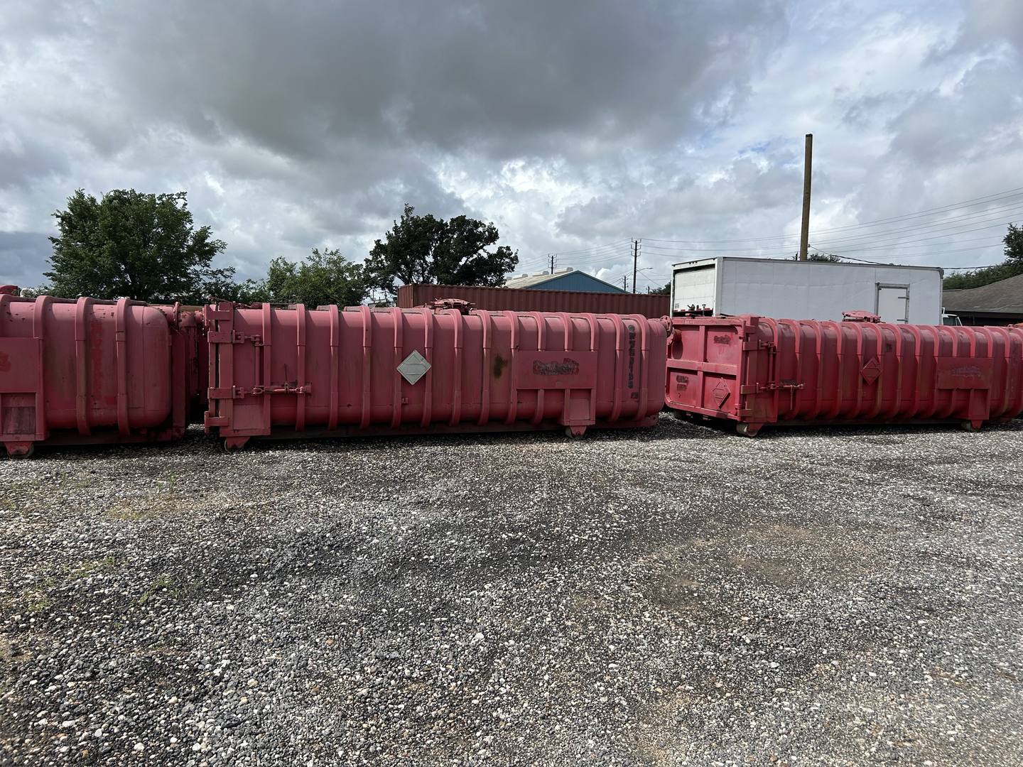 Several used Roll-Off Vacuum Tanks, side view