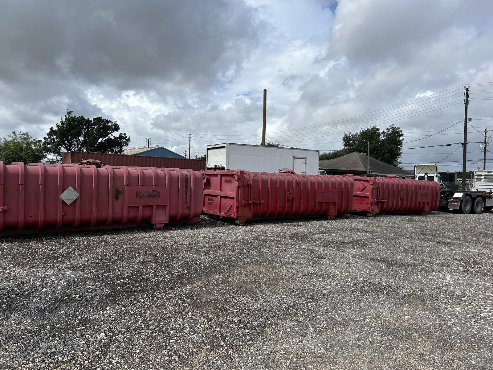 Used red Roll-Off Vacuum Tanks with ribbed sides in our yard