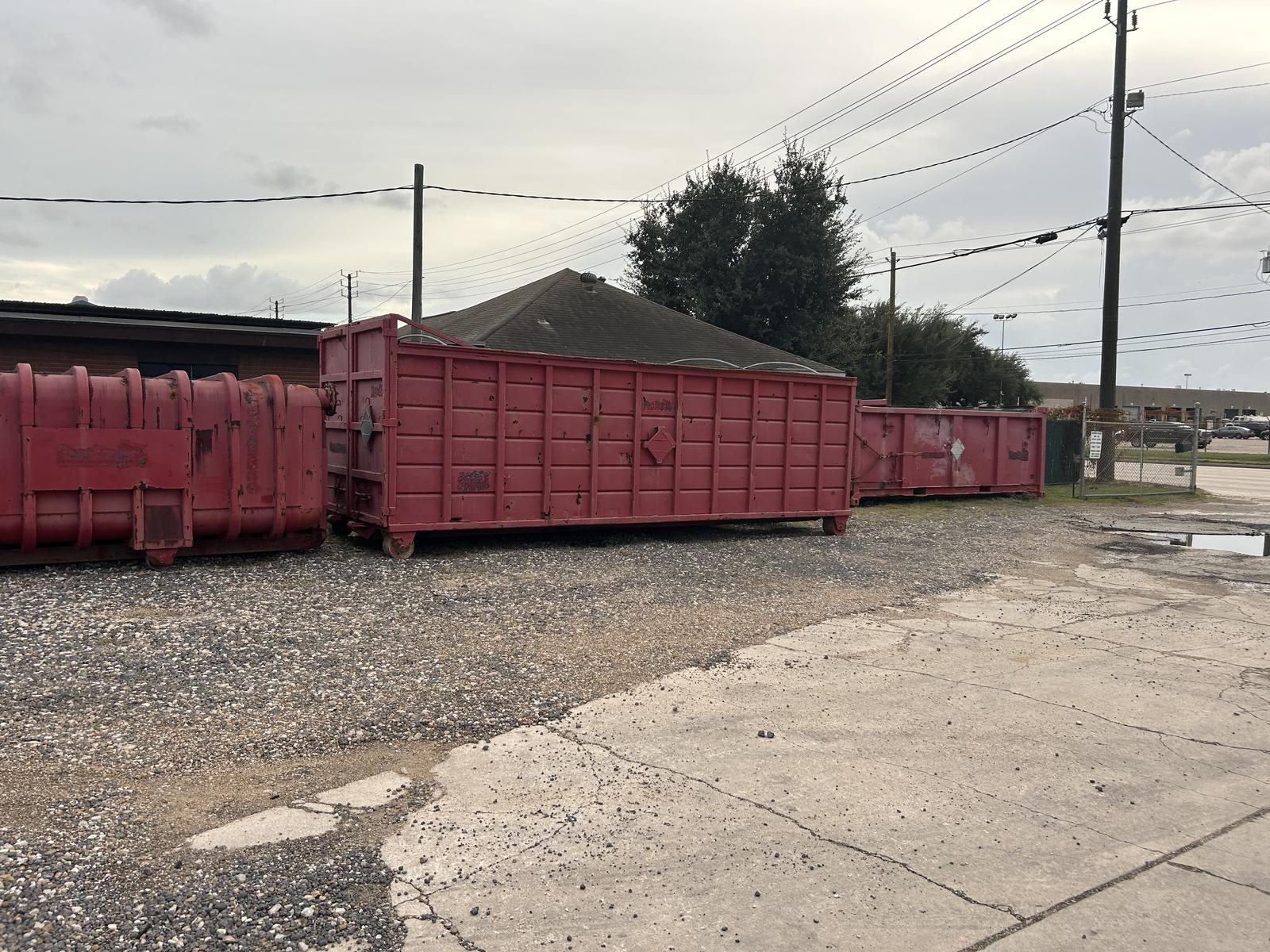 Row of used red roll-off containers in the yard